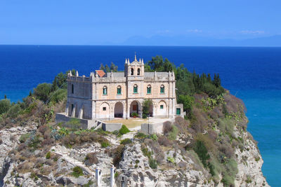 Buildings by sea against blue sky