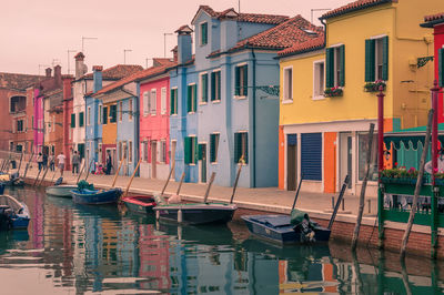 Boats moored in canal by buildings in city