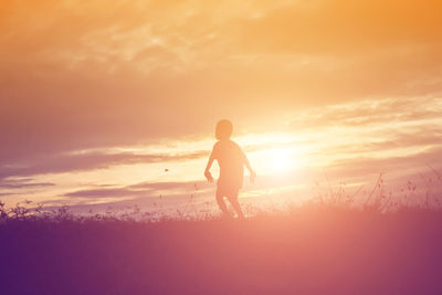 Silhouette man standing on land against sky during sunset