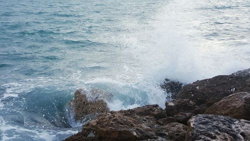 High angle view of waves breaking against rocks in sea