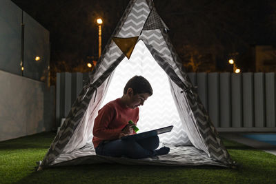 Little kid reading a book on a indian tent at night