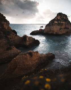 Rocks on sea shore against sky