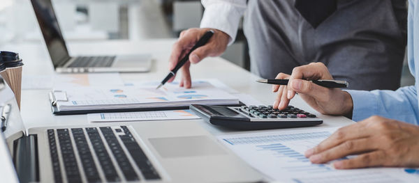 Midsection of businessman using laptop on table