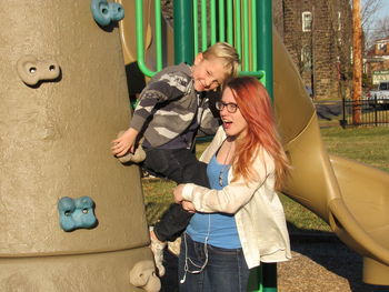 Teenage girl carrying brother at playground