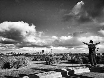 Rear view of man looking at cityscape against sky