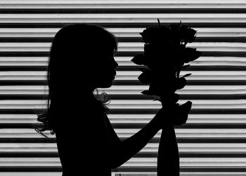 Girl of 5 years old is staying close to the vase with roses. black and white