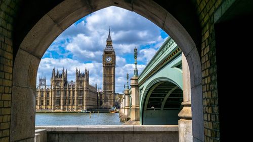 Big ben in front of thames river seen though arch