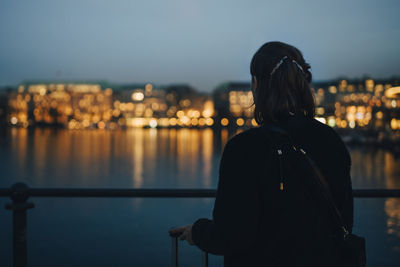 Rear view of woman standing by railing against sky