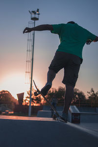 Rear view of man skateboarding in city against sky