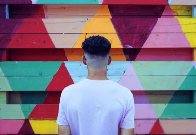 Rear view of man standing against multi colored wall