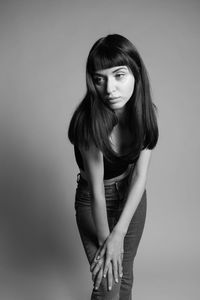 Portrait of woman standing against gray background