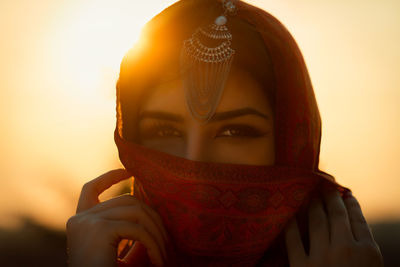 Close-up of beautiful young woman against sky during sunset