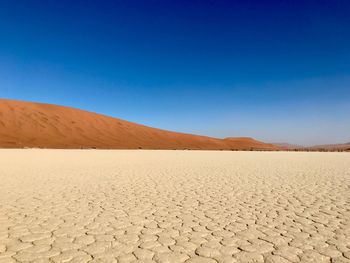 Scenic view of desert against clear blue sky