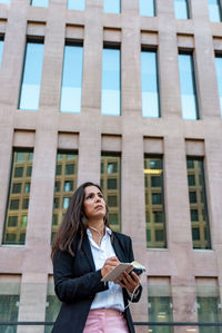 Low angle view of woman standing against building in city