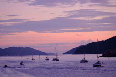 Silhouette sailboats in sea against sky during sunset