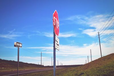 Low angle view of road sign against blue sky