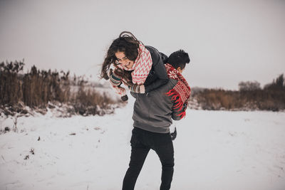 Rear view of woman standing on snow covered field