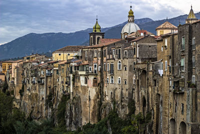 Old buildings in city against mountains