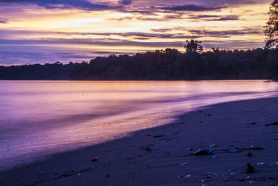 Scenic view of beach against sky at sunset