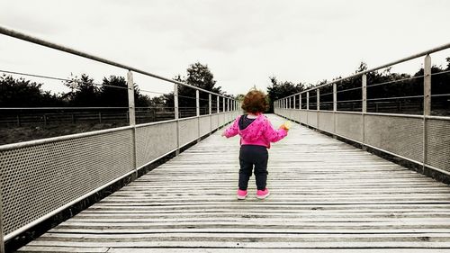 Rear view of woman walking on footbridge