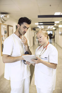 Doctors discussing over digital tablet in hospital corridor