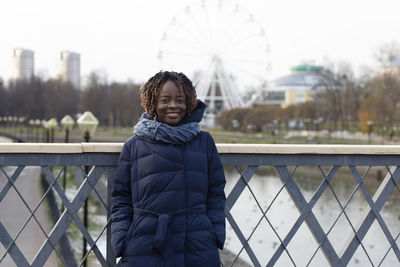 Portrait of smiling man standing on railing during winter