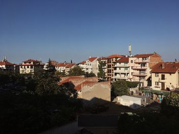 Buildings in city against clear blue sky