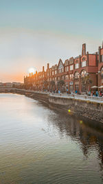 Buildings by river against clear sky