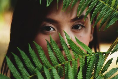 Close-up portrait of young woman looking through plants