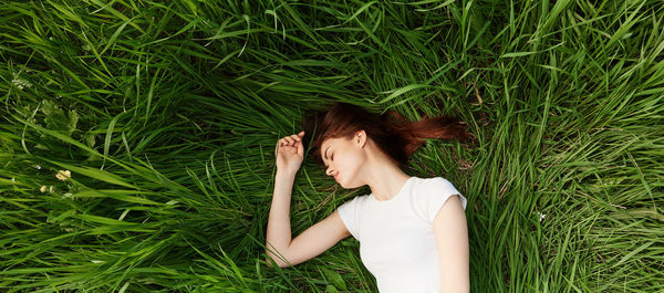 Side view of young woman sitting on grassy field