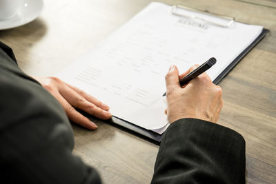 Midsection of man reading book on table