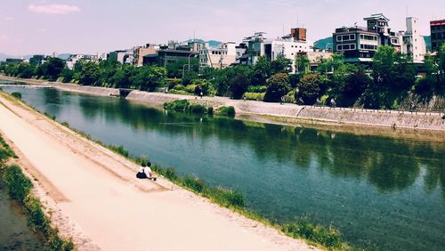 Scenic view of river by city against sky