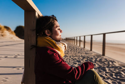 Young woman with eyes closed relaxing at beach at sunset. holidays and relaxation concept