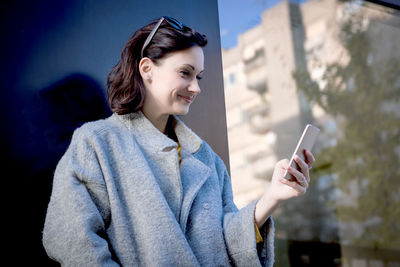Young woman using smart phone while standing outdoors