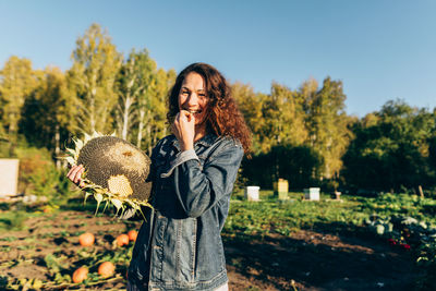Smiling woman savoring sunflower seed, embracing simple pleasures of rural life