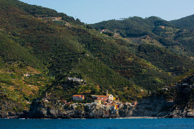 Scenic view of sea by mountains against clear sky