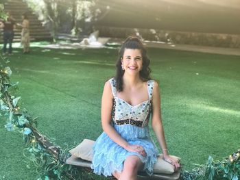 Portrait of smiling young woman sitting on swing in playground