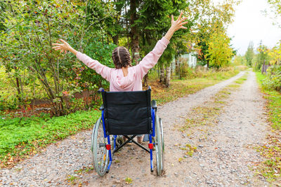 Young happy handicap woman in wheelchair on road in hospital park enjoying freedom