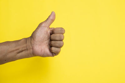 Close-up of human hand against yellow background