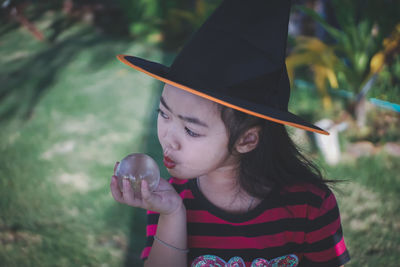 Girl wearing witch hat holding crystal ball