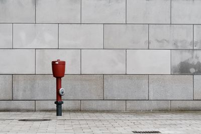 Red fire hydrant on footpath against wall