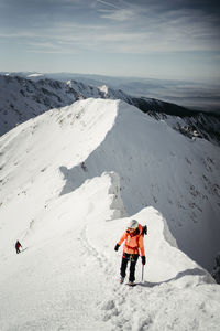 Rear view of man walking on snowcapped mountain