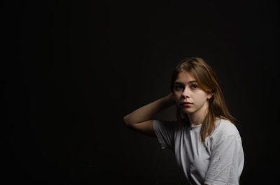 Young woman standing against black background