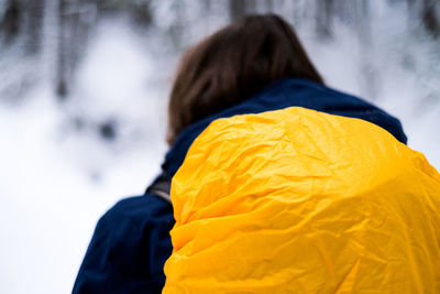 Part of woman wearing backpack in front of snow covered landscape