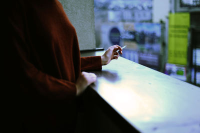 Midsection of woman holding cigarette at lobby