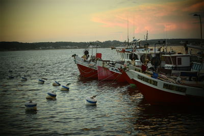 Boats moored on sea against sky during sunset