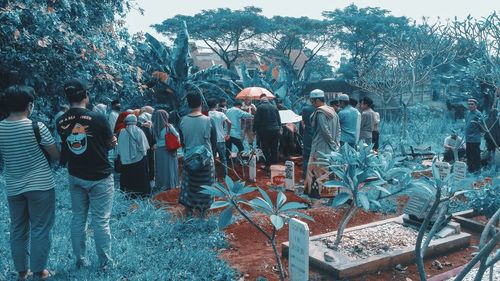 Rear view of people standing against plants