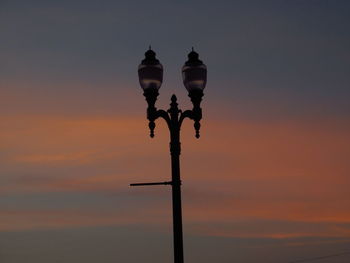 Silhouette lamp post against dramatic sky during sunset