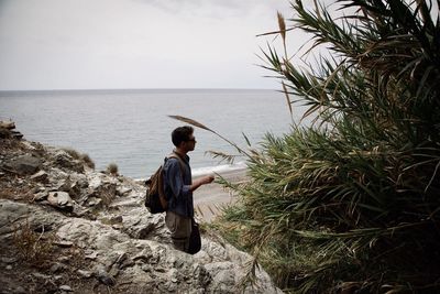 Rear view of man looking at sea against sky