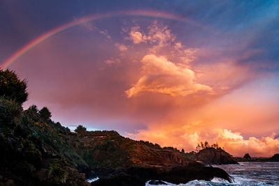 Scenic view of rainbow over sea against sky during sunset
